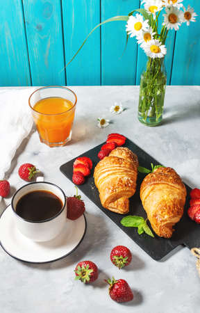 Tasty breakfast. Fresh croissants and strawberries, black coffee and orange juiceの写真素材