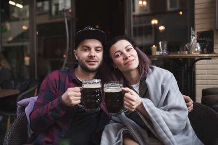 Happy man and woman holding cups of beer and cheering for their love
