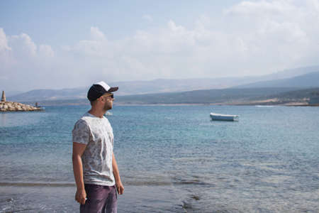 Traveling by Cyprus. Young man enjoying the view of bay on the sea promenade.