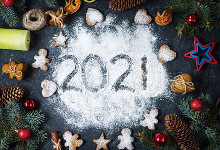 Happy New Year 2021 written on flour and Christmas Decorations Gingerbread cookies on dark stone background. Christmas, New Year greeting cardの写真素材