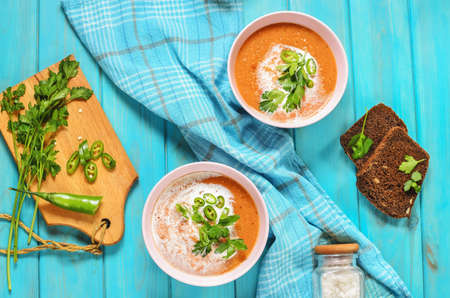 Red lentil tomato soup - delicious vegetarian food on blue wooden background. Healthy lunch. Top...