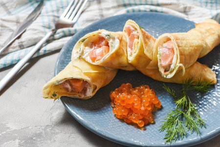 Delicious breakfast - crepes with smoked salmon, sour cream and caviarch on concrete background.の写真素材
