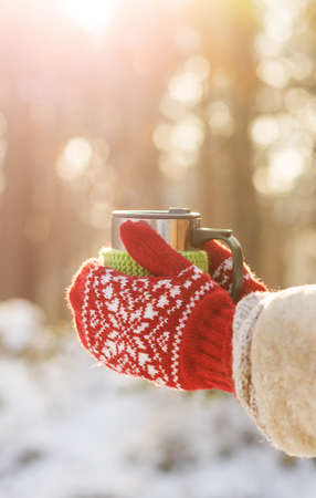 Side view of female hand holding hot cup of coffee or tea in winterの写真素材