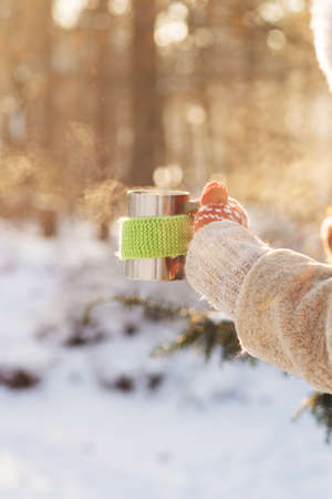 Side view of female hand holding hot cup of coffee or tea in winterの写真素材