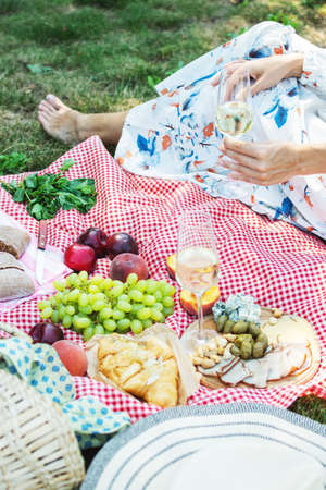 Cropped picture of a girl sitting on a grass on nature. Concept of having a picnic in a city park during summer weekends.の写真素材
