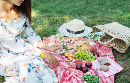 Cropped picture of a girl sitting on a grass on nature. Concept of having a picnic in a city park...