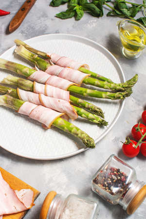 Fresh green asparagus wrapped in bacon on a gray concrete tableの写真素材