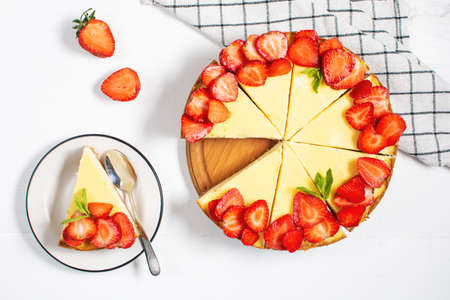 Piece of cheesecake with fresh strawberries jam and mint. Tasty homemade cheesecake on a white background. top viewの写真素材