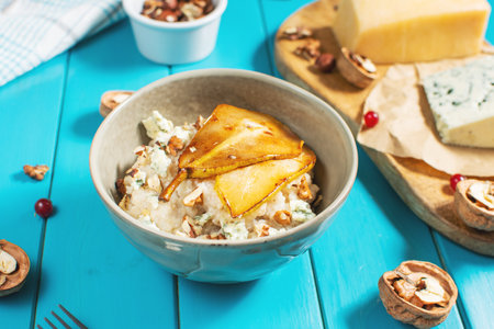 Pear and gorgonzola oatmeal with walnuts on blue wooden table.の写真素材