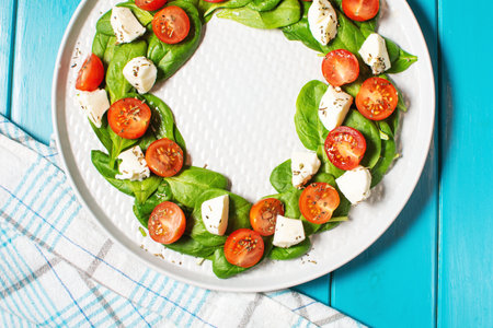 Italian caprese salad with tomatoes, mozzarella, basil, olive oil on a blue wooden background. top view. Italian food.の写真素材