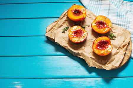 Baked peaches with honey and cinnamon on blue wooden background. summer dessert. Top view and copy spaceの写真素材