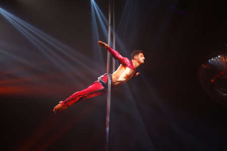 Brazilian strong sexy man do performance on aerial silks in red lights