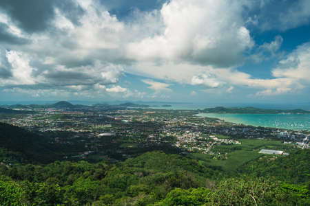 Top view of the city on a tropical island surrounded by green hills and the sea, cloudy weatherの写真素材