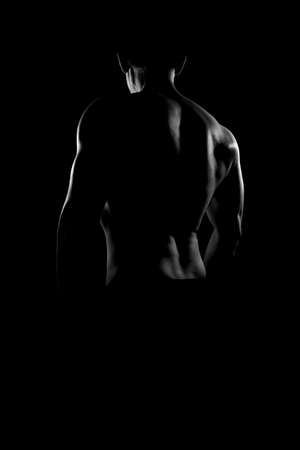 Rear view of young muscular man in black and white. Nude silhouette of Back.の写真素材