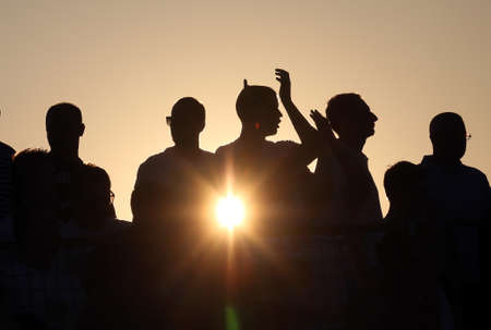 Poeple silhouettes cheering at sunsetの写真素材