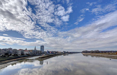 Town Osijek, wiew from walking bridge on city and river Drava, reflection of blue sky with clouds in water.のeditorial素材