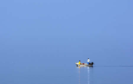 Man in the boat on foggy seeの写真素材
