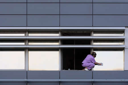 Cleaning woman cleaning windows on gray buildingの写真素材