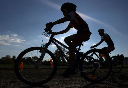 Silhouette of child and man riding bikeの写真素材