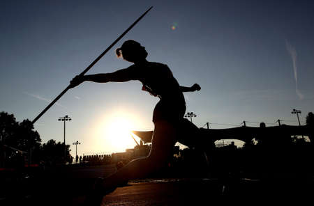 A woman silhouette throws a javelin during athletics competitionの写真素材
