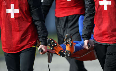 The medical staff transfers the injured football player on stretcher during the soccer match.の写真素材