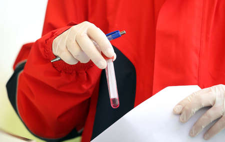 Medical staff member with mask and protective equipment holds Coronavirus nasal swabs test tubes at drive-through testing point in an effort to curb the spread of COVID-19 (novel coronavirus)の写真素材