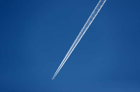 Passenger plane leaves a white trail in the skyの写真素材