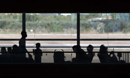 Silhouettes of people with masks sitting and waiting at the Split airport terminal