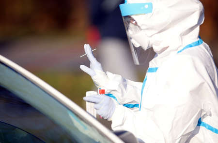 Medical staff member with mask and protective equipment performs fast antigen testing for SARS-CoV-2...