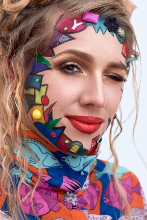 Close up portrait of young beautiful woman, model,  clown. Bright creative fantasy makeup, geometric shapes, circles. Multicolored paint, red, blue, orange, yellow, pink. Pop art style, avant garde.の写真素材