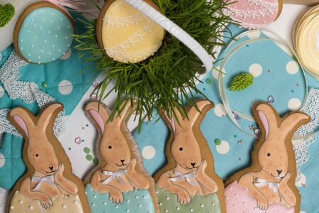 sweet easter multicolored baby rabbits in eggs, honey-cakes,green grass in busket, lying on table,...