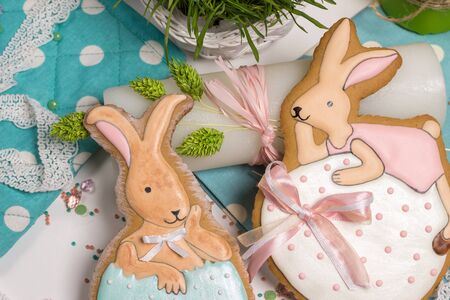 sweet easter multicolored baby rabbits on eggs, honey-cakes, lying on table,  blue dots tablecloth, family celebration food photographyの写真素材