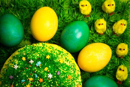 Easter celebrating sweet  cake decorated with sugar sprinkling on green fress grass with yellow toy chickens, holidays food photographyの写真素材