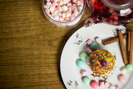Celebrating plate with marshmallows, sweet cake, candies, fresh fruit tea, cinnamon on wooden table, birthday party, holiday family photoの写真素材