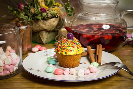Celebrating plate with sweet cupcake, candies, fresh fruit tea, cinnamon on wooden table, birthday party, holiday family photoの写真素材