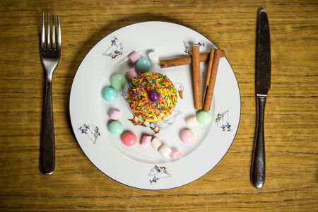 Celebrating plate with marshmallows, sweet cake, candies, cinnamon on wooden table, birthday party, holiday family food photographyの写真素材