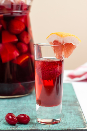 Summer fruit wine, sangria cocktail in small glass and jugful, fresh dogwood berries, grapefruit decoration, food photoの写真素材