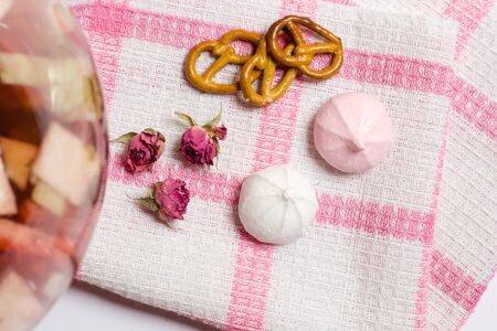 Pink cookies, murhmellows, dry roses on tablecloth, glass with fruits, tasty food photoの写真素材