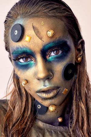 Cosmic unusual makeup with decorative elements on face, golden skin, creative concept makeup, stylish look, studio photoの写真素材