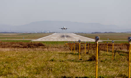 Runway of airport. Plane takes off. Several searchlights in the foreground for night illumination. Aviation and transportation.の写真素材