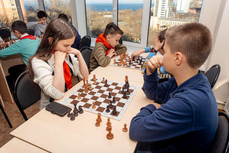 Russia, Vladivostok, 12/01/2018. Kids play chess during chess competition in chess club. Education, chess and mind games. Competition and tournament. Kids' leisure.のeditorial素材