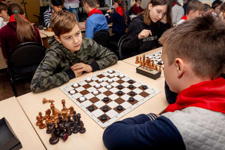 Russia, Vladivostok, 12/01/2018. Kids play chess during chess competition in chess club. Education, chess and mind games. Competition and tournament. Kids' leisure.のeditorial素材