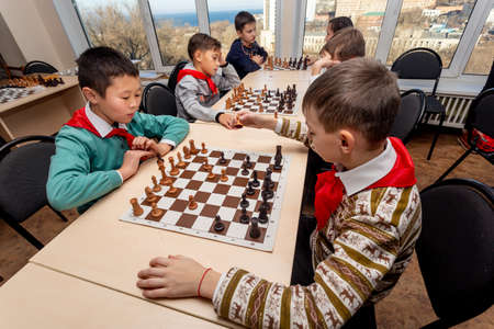 Russia, Vladivostok, 12/01/2018. Kids play chess during chess competition in chess club. Education, chess and mind games. Competition and tournament. Kids' leisure.のeditorial素材