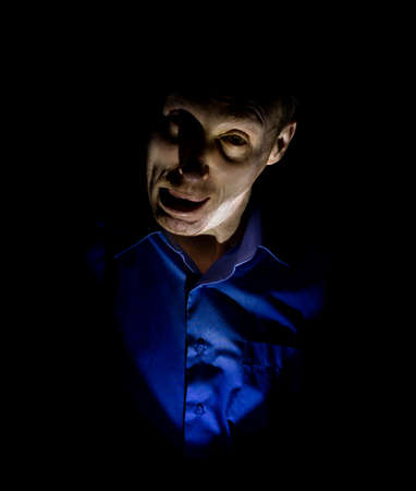 Stylish dark portrait of adult caucasian man who seems like maniac or psycho. Isolated on black background. Low-key lighting.の写真素材