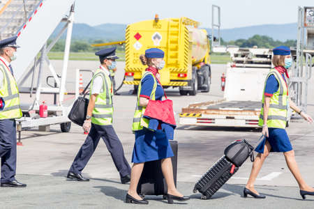 Russia, Vladivostok, 08/17/2020. Crew of airplane in official uniform and medical masks goes to board of plane. Crew of plane. Aviation and transportation. Plane crew protection against COVID-19.のeditorial素材