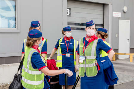 Russia, Vladivostok, 08/17/2020. Nice stewardesses of plane in official uniform of Rossiya Airlines and medical masks before boarding. Aviation and transportation. Crew protection against COVID-19.のeditorial素材