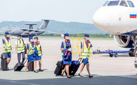 Russia, Vladivostok, 08/17/2020. Crew of airplane in official uniform and medical masks goes to board of plane. Crew of plane. Aviation and transportation. Plane crew protection against COVID-19.のeditorial素材
