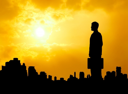 silhouetted business man standing over urban city looking forward and hope successの写真素材