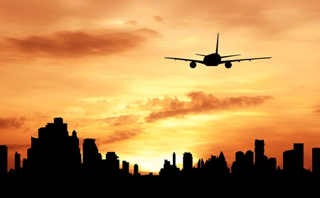 silhouette of commercial plane fly over city during sunriseの写真素材