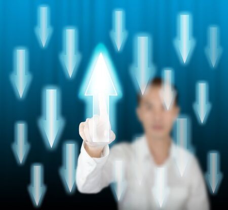 business man pointing rising arrow against others falling on modern digital screenの写真素材